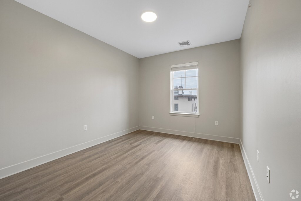 A room with a window and wooden flooring.