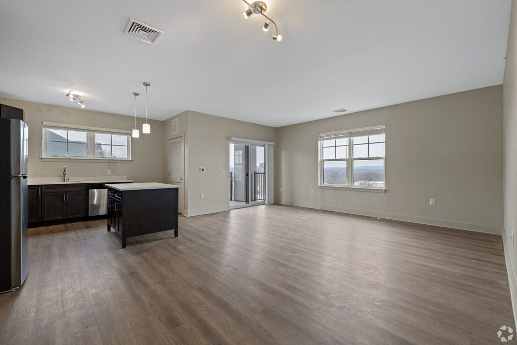A spacious kitchen with dark wood floors and a large island.