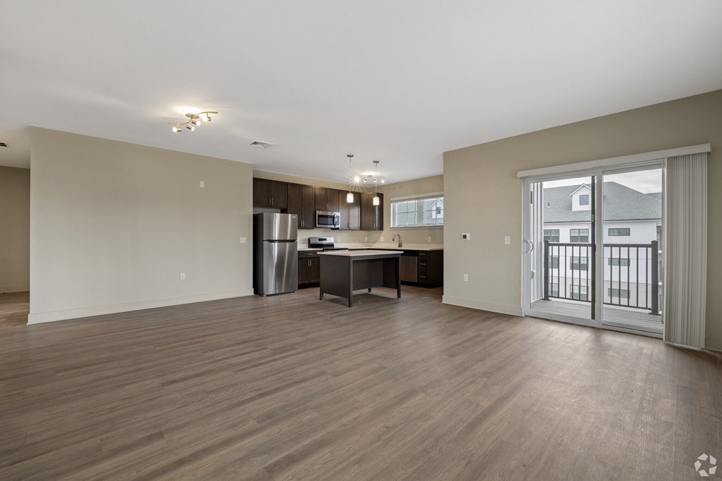 A spacious living room with a kitchenette and a dining table.