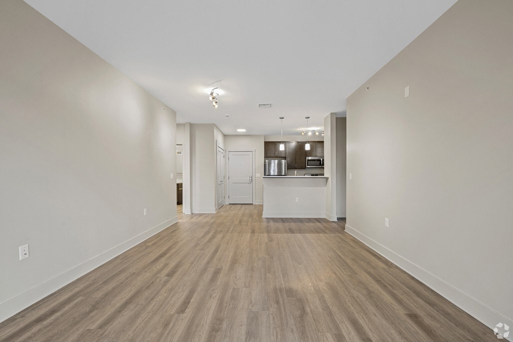 A long, empty hallway with wood flooring and white walls.