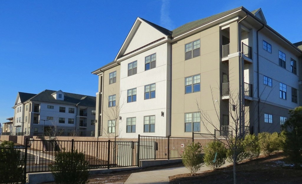 A large apartment complex with a black fence in front.