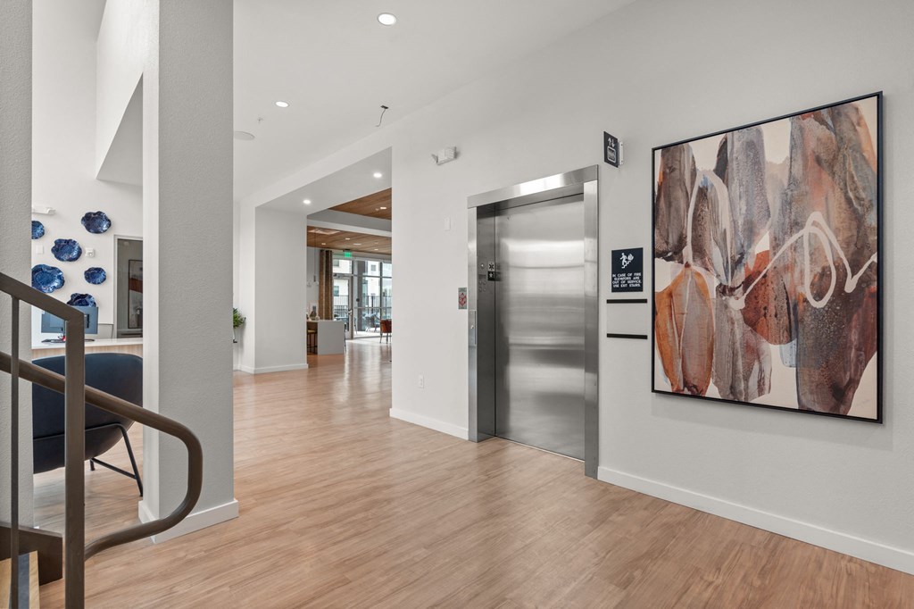 A hallway with a staircase and a painting on the wall.
