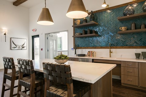 A kitchen with a white counter top and brown chairs.