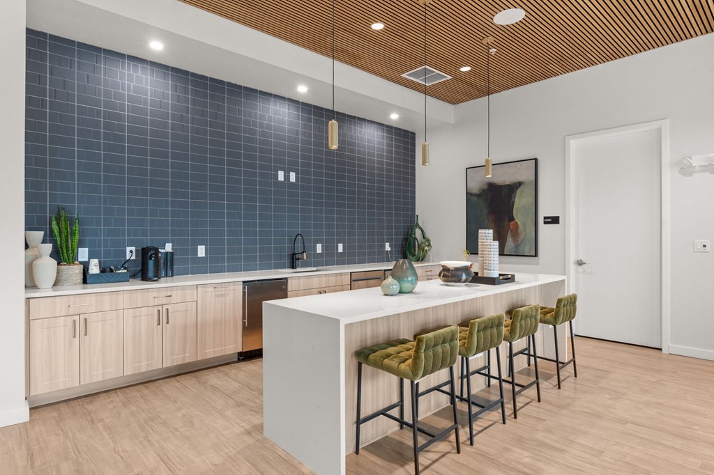 A kitchen with a bar and chairs.
