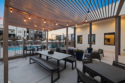 A patio with a table and chairs is covered by a roof with lights.