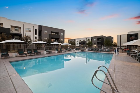 A large swimming pool with a diving board and lounge chairs.