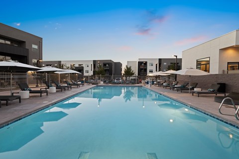 A large swimming pool surrounded by lounge chairs and umbrellas.
