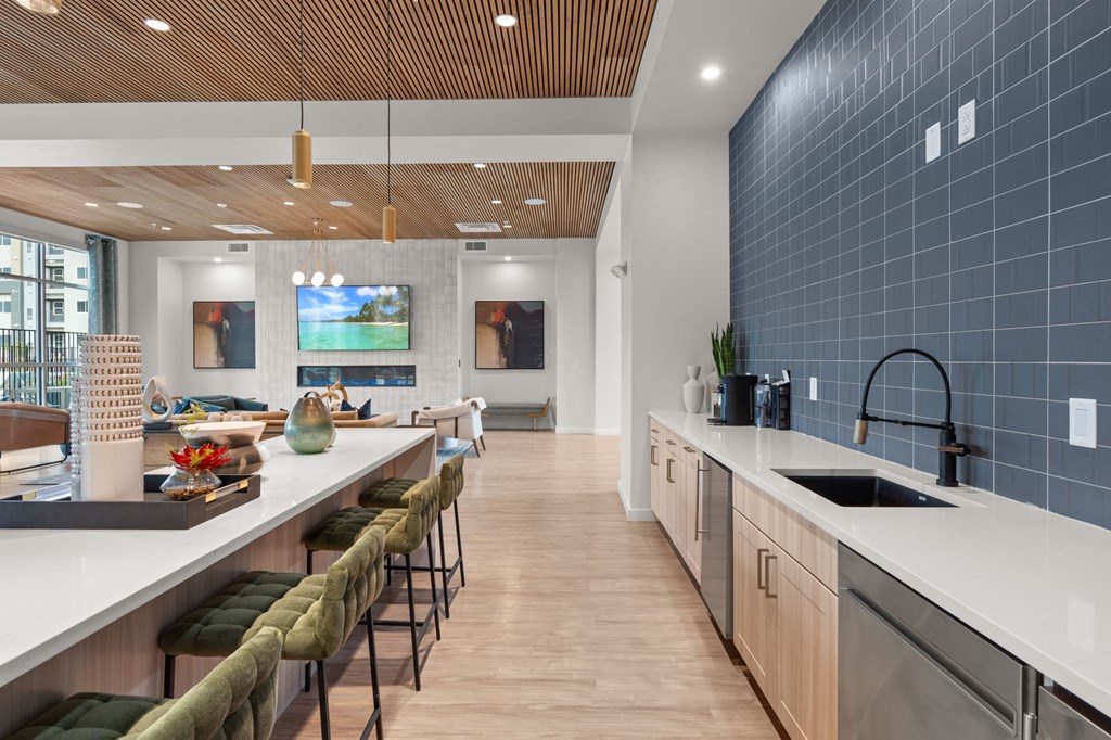 A modern kitchen with a long counter and bar stools.