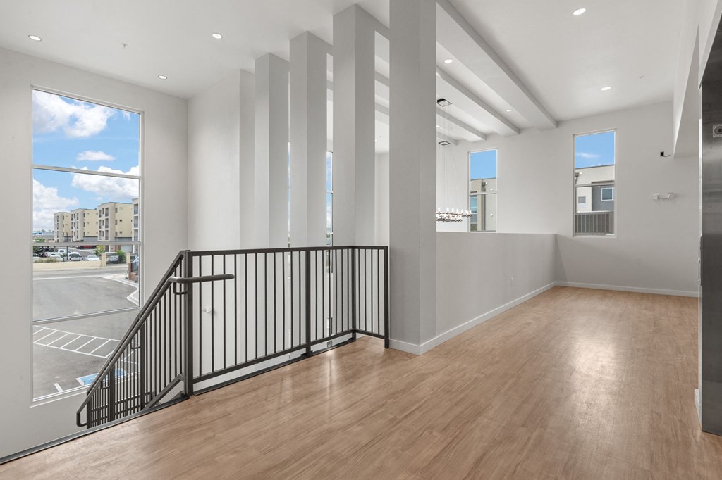 A room with a wooden floor and a balcony with a black railing.