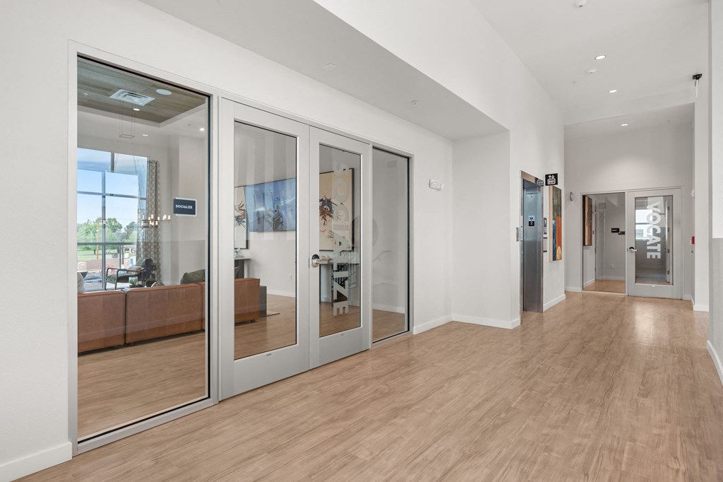 A hallway with a glass door and a wooden floor.