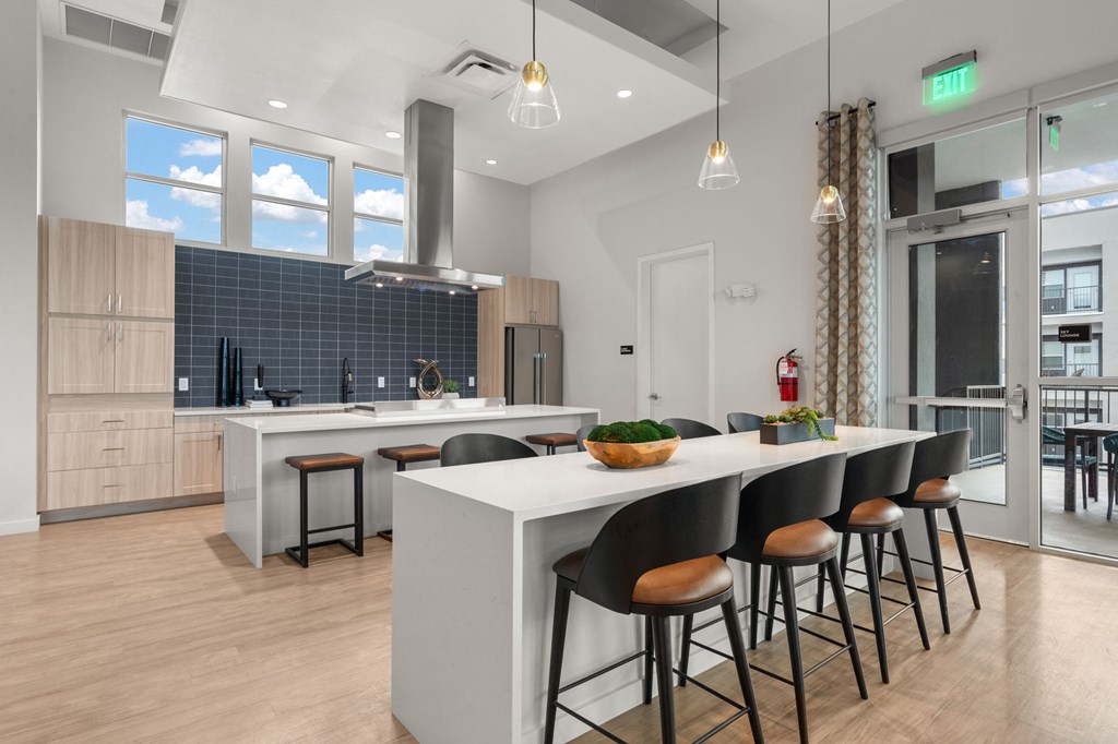 A modern kitchen with a long white island and black barstools.