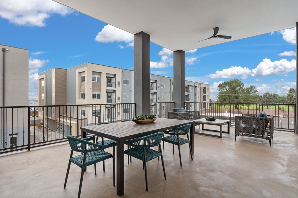 A patio with a table and chairs overlooks apartment buildings.