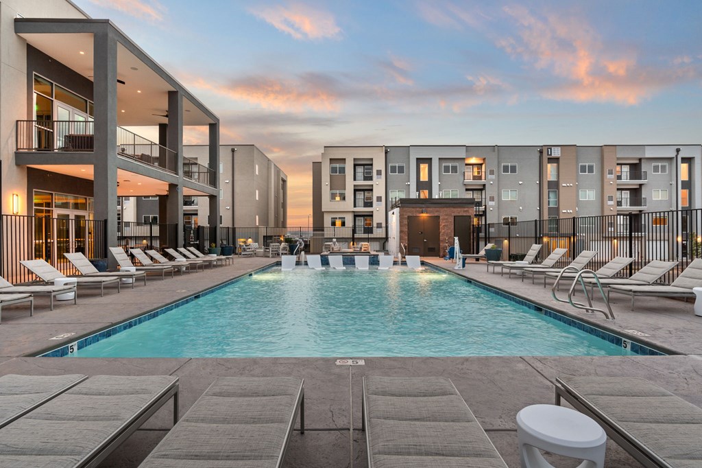A swimming pool surrounded by lounge chairs and buildings.