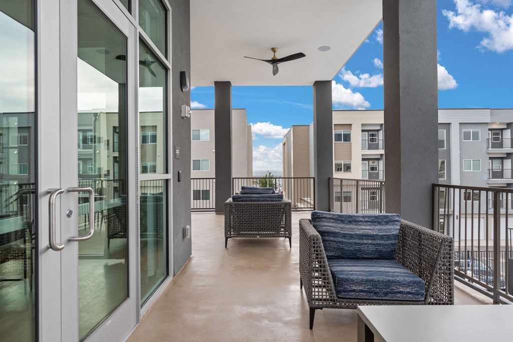 A balcony with a table and chairs overlooks a building.