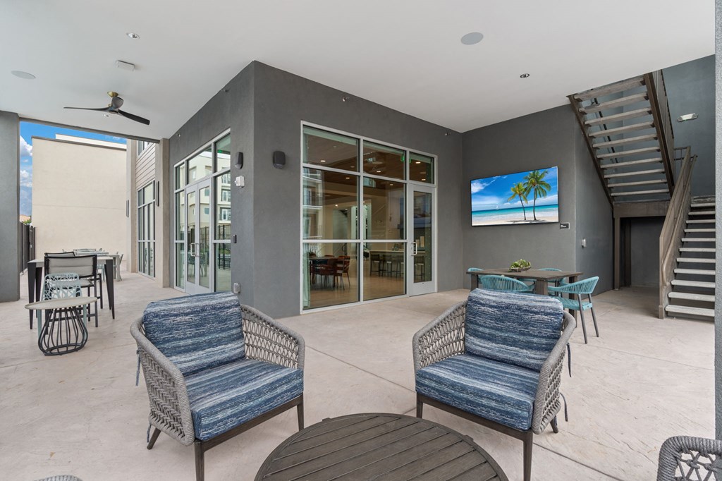 A patio with a table, chairs and a television.
