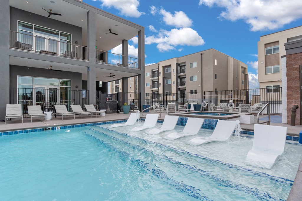 A swimming pool with white lounge chairs and a building in the background.