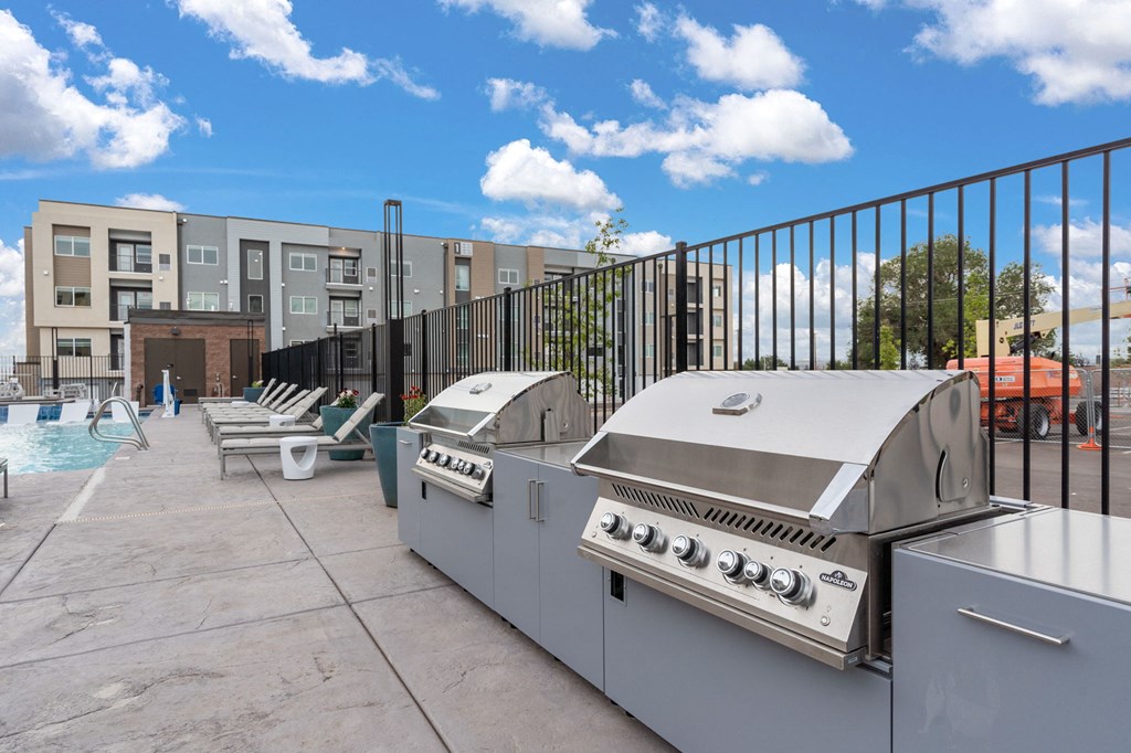 A BBQ grill is on a patio next to a pool.
