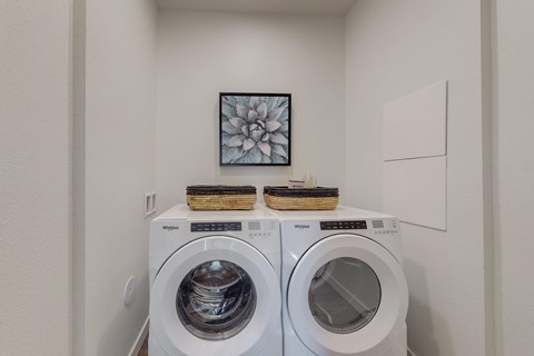 Two white front loading washing machines in a laundry room.