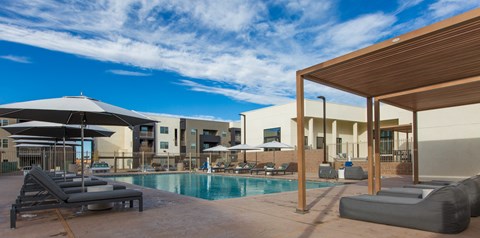 A pool area with sun loungers and a wooden pergola.