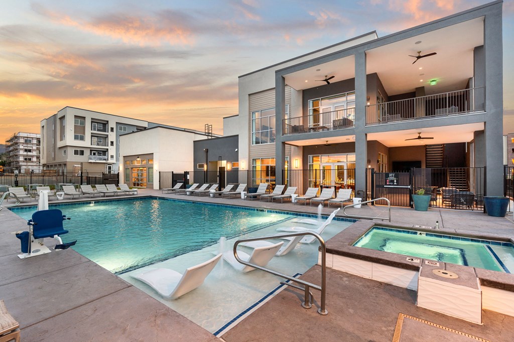 A modern building with a pool and lounge chairs.