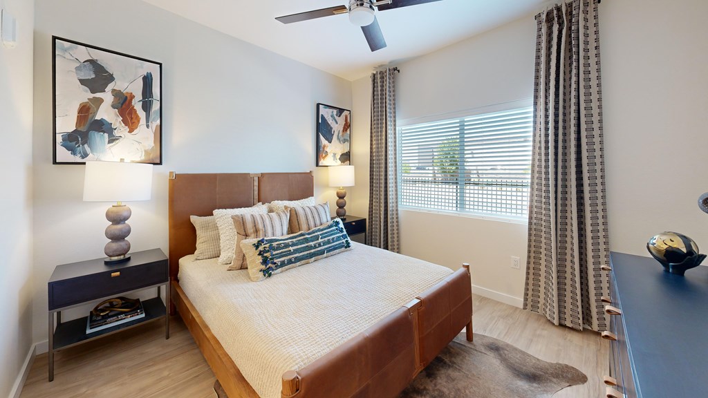 A bedroom with a bed, nightstand, and a ceiling fan.