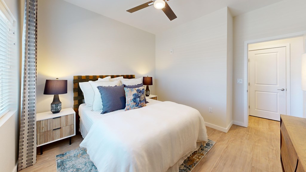 A bedroom with a bed, nightstand, and a fan.