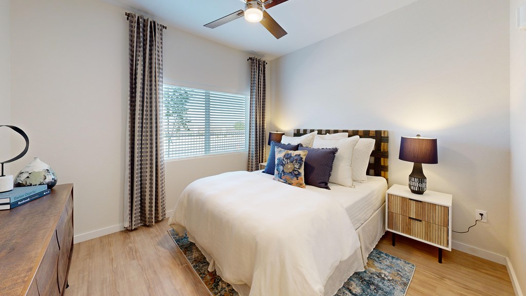 A bedroom with a large bed, a nightstand, and a ceiling fan.