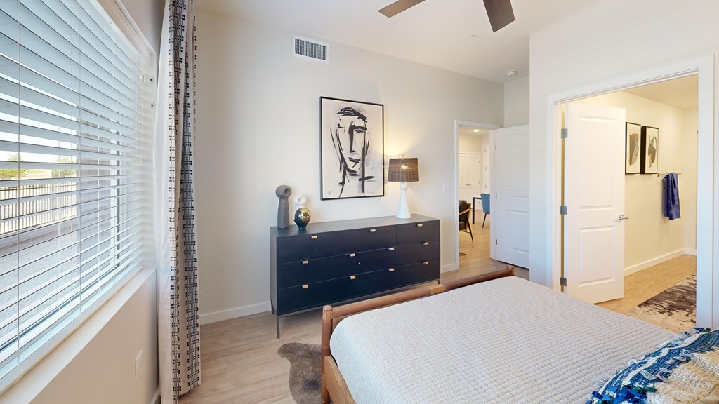 A bedroom with a bed, dresser, and a painting on the wall.