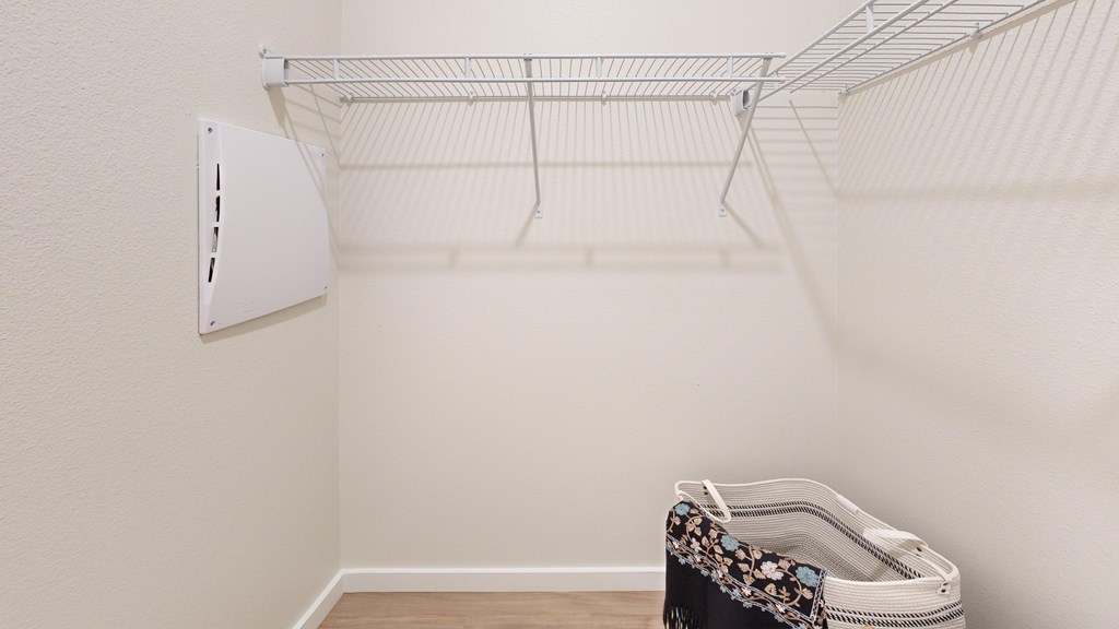 A white wall with a white shelf and a black and white bag on the floor.