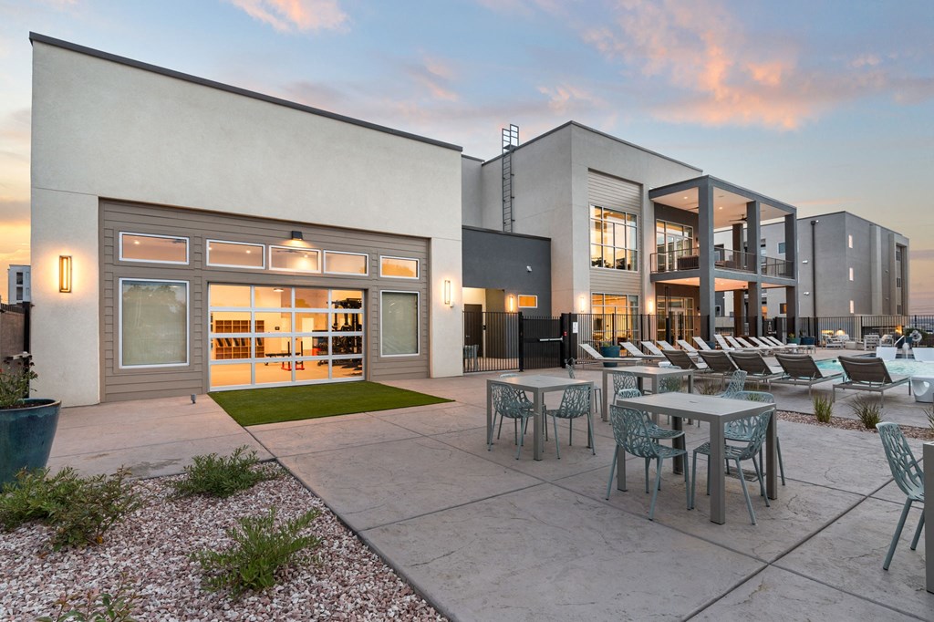 A modern building with a patio and chairs.