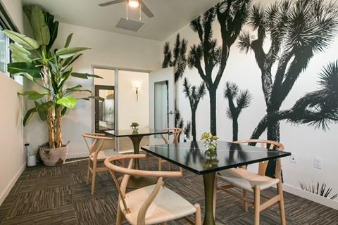 A dining room with a table and chairs and a tree mural on the wall.