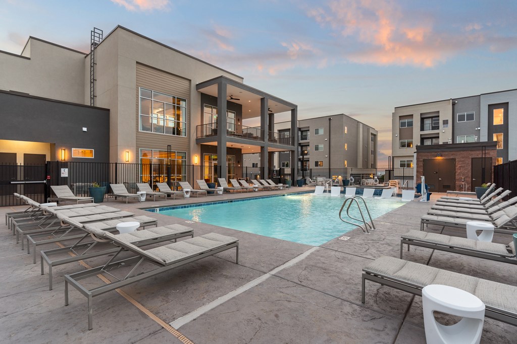 A pool surrounded by sun loungers and apartment buildings.