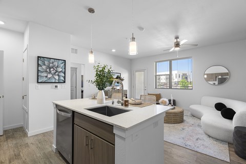 A modern kitchen with a large island and a living area with a sofa.