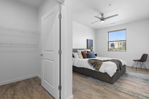 A bedroom with a bed, chair, and a window.