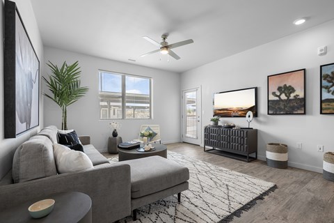 A living room with a grey couch, a coffee table, and a ceiling fan.