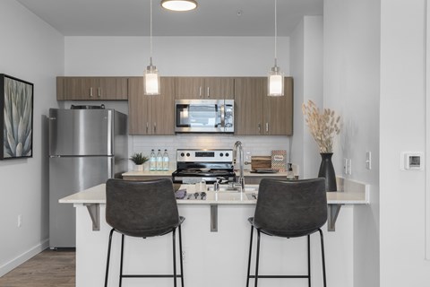 A modern kitchen with a white countertop and two black barstools.