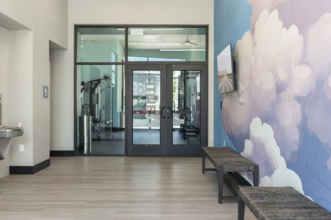 A gym with a row of treadmills and a wall mural.