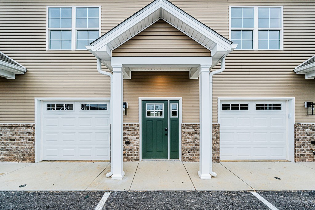 A house with a green door and white garage doors.