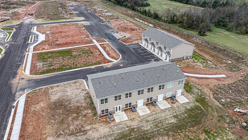 A large building with a grey roof is surrounded by a parking lot and a road.