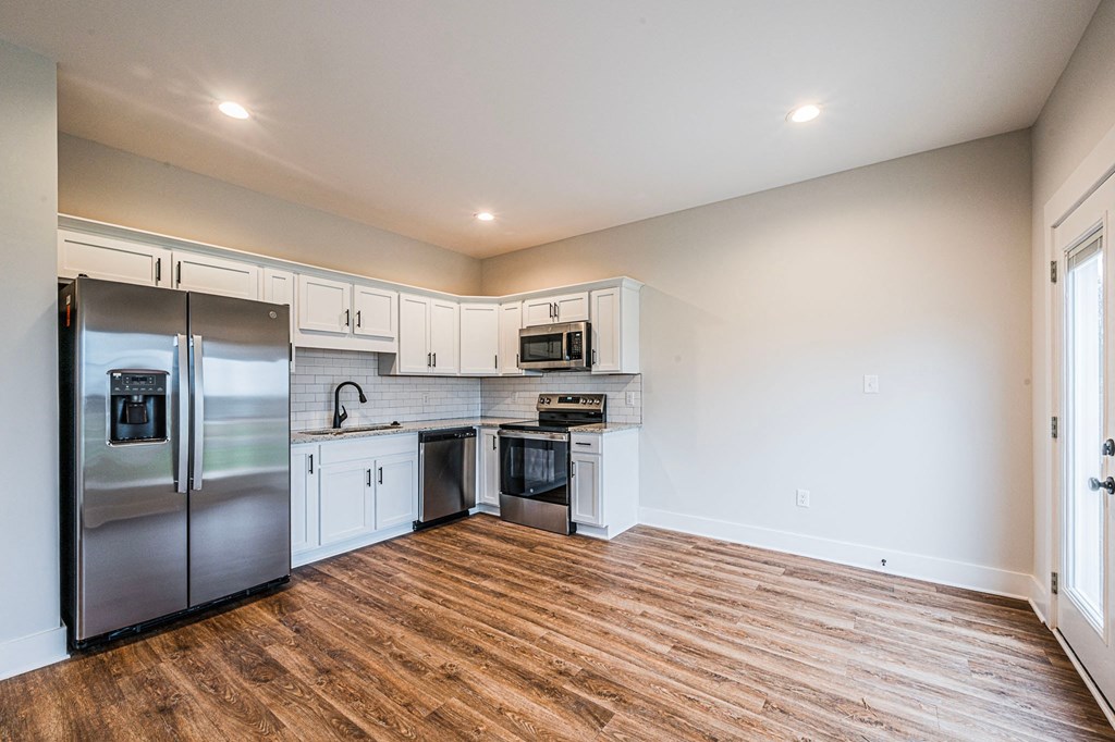 A kitchen with a refrigerator, microwave, oven, and cabinets.