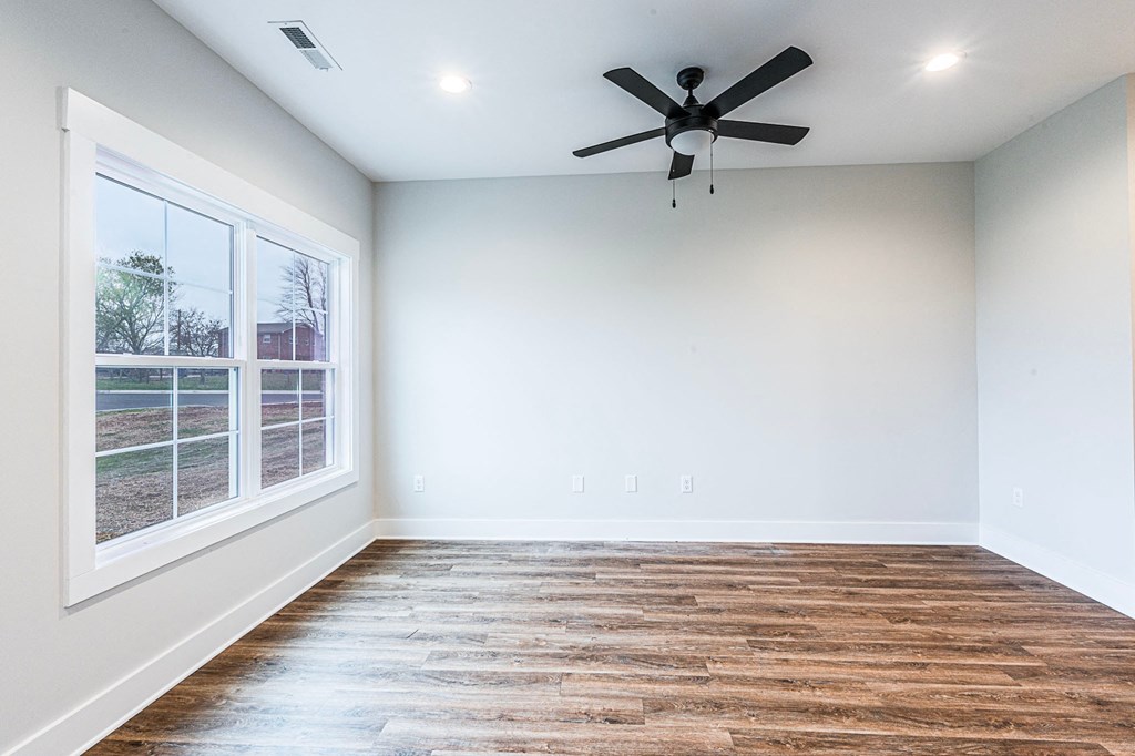A room with a ceiling fan and a window overlooking a yard.