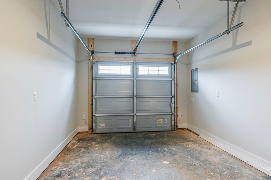 A garage door is open in a room with a concrete floor.