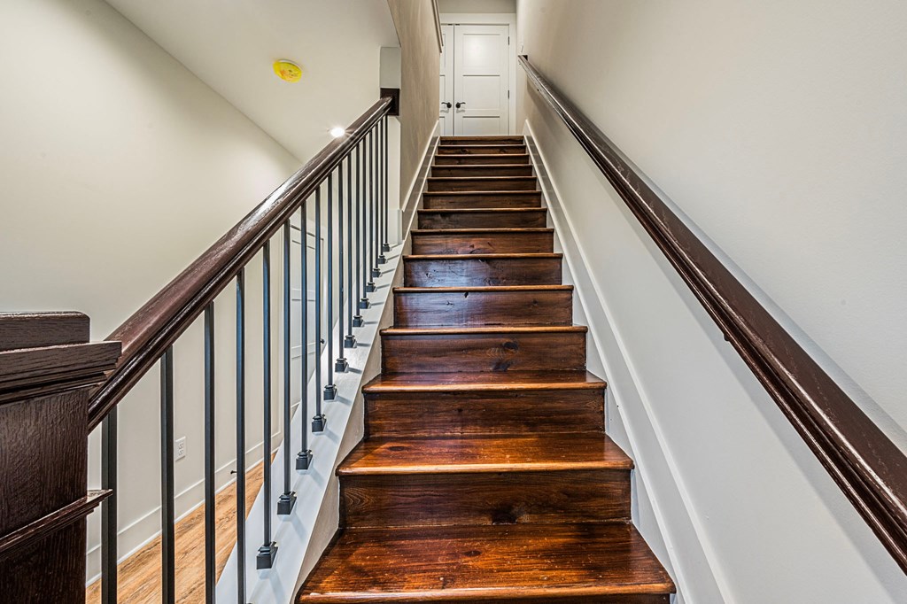 A long flight of wooden stairs with a metal railing on the left side.