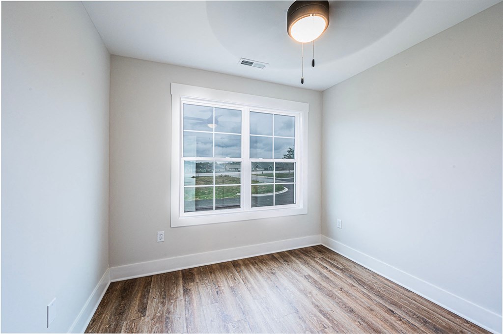 A room with a window and wooden flooring.