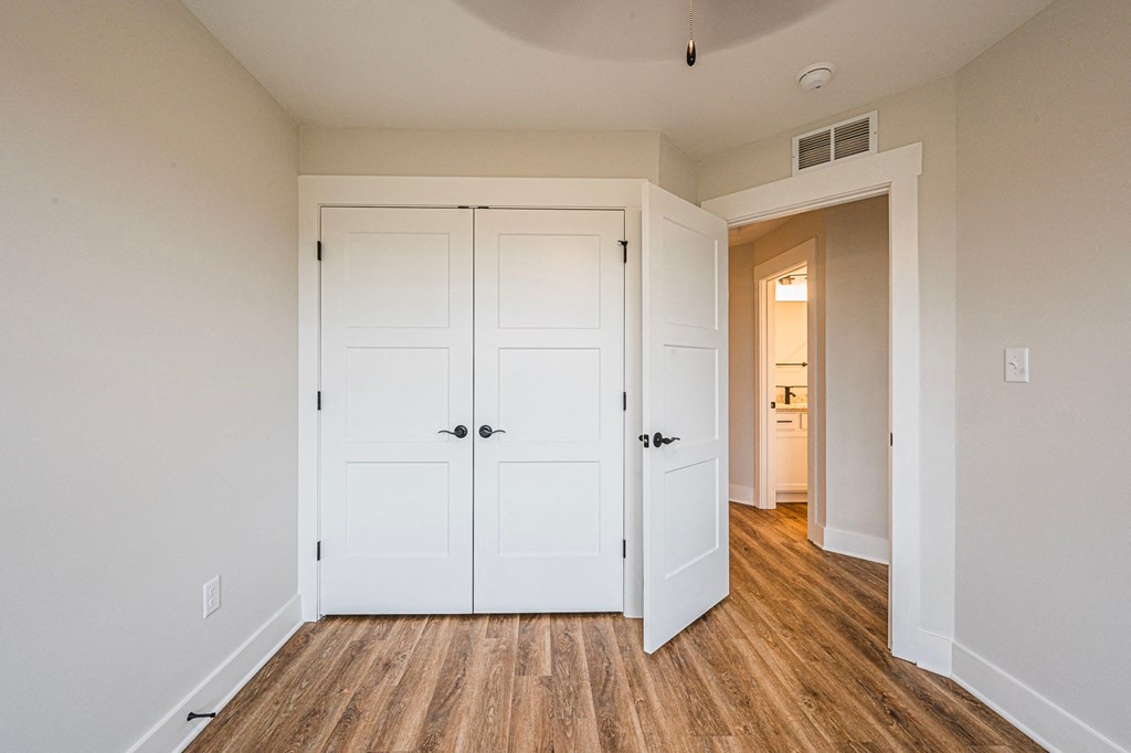 A room with a white door and a wooden floor.