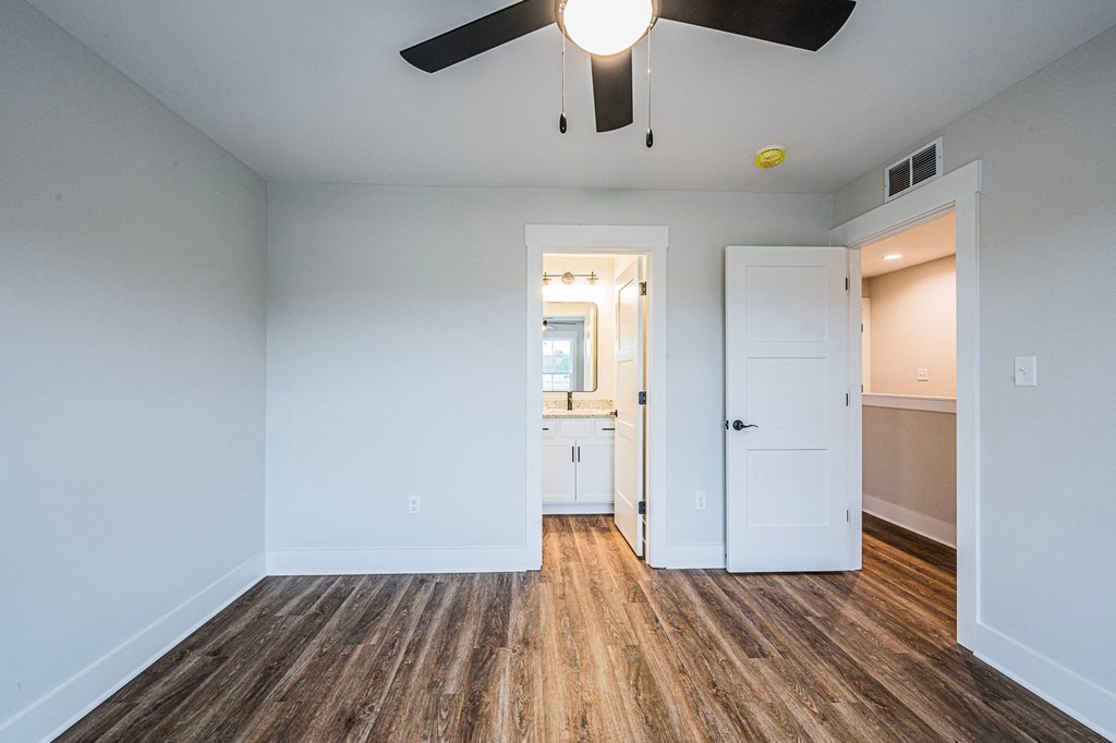 A room with a ceiling fan and wooden floors.