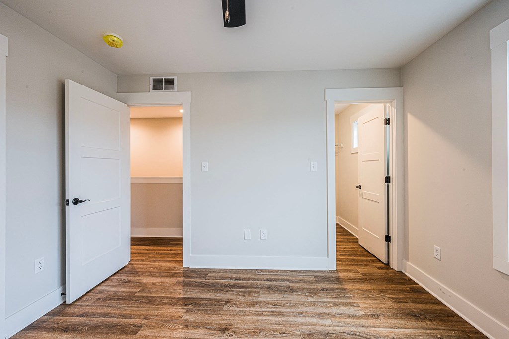 A room with a white door and a brown floor.