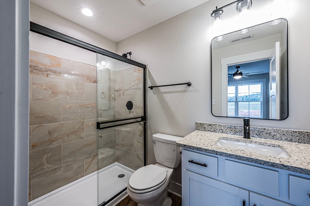 A bathroom with a toilet, sink, and mirror.