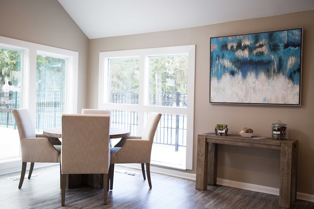 a dining room with a table and chairs and a painting on the wall