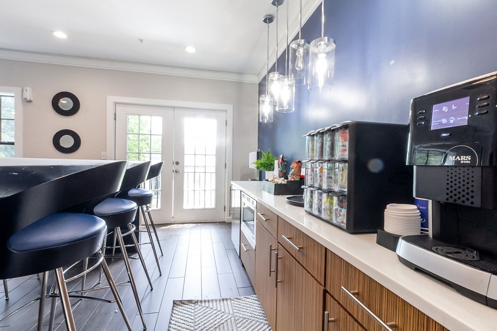 a kitchen with a counter top with a coffee machine and chairs